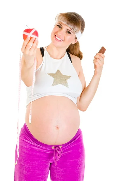 Jabłko lub czekolady? kobieta w ciąży wybór zdrowego stylu życia — Zdjęcie stockowe