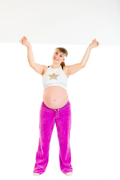 Smiling beautiful pregnant woman holding blank billboard over her head — Zdjęcie stockowe