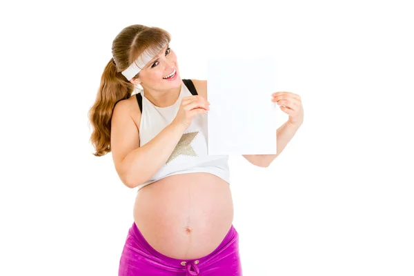 Улыбающаяся красивая беременная женщина держит пустую белую бумагу над головой — стоковое фото