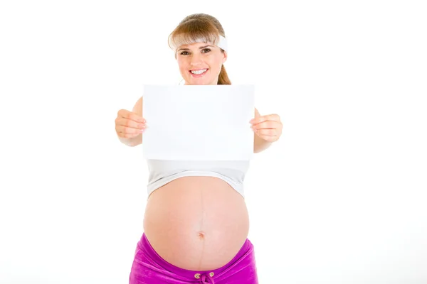 Sorrindo bela mulher grávida segurando papel branco vazio — Fotografia de Stock