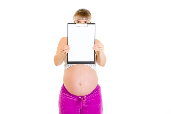 Zwangere vrouw met lege Klembord voor haar gezicht — Stockfoto