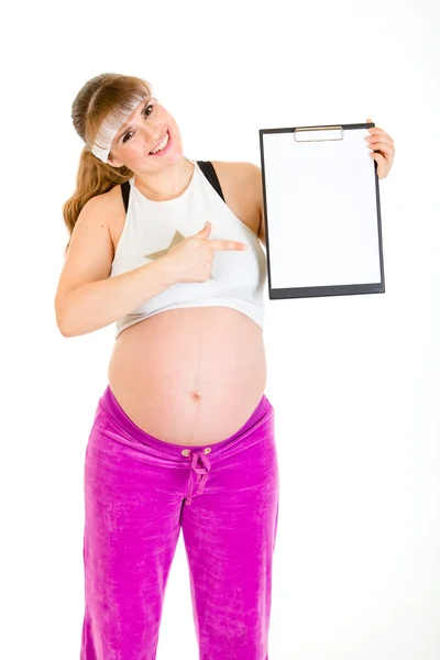 Sonriendo hermosa mujer embarazada señalando en el portapapeles en blanco — Foto de Stock