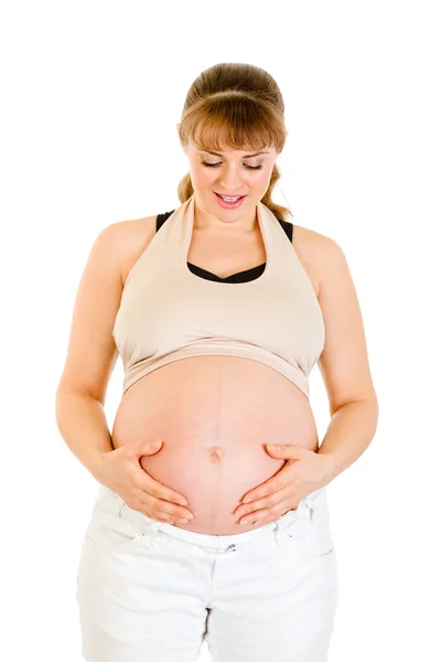 Sorridente donna incinta tenendo la pancia isolata su bianco — Foto Stock