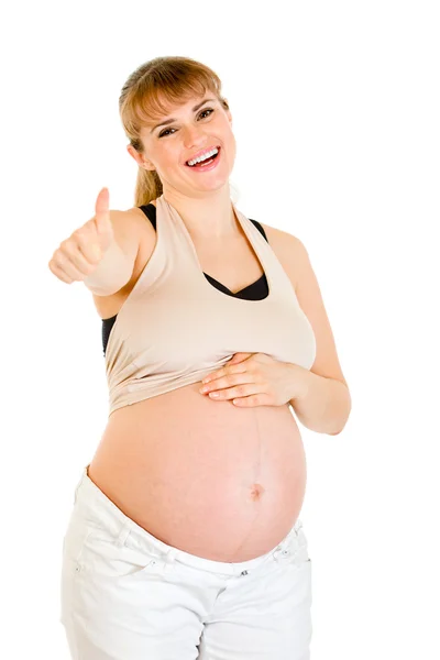 Sonriendo mujer embarazada tocando su vientre y mostrando los pulgares hacia arriba gesto — Foto de Stock