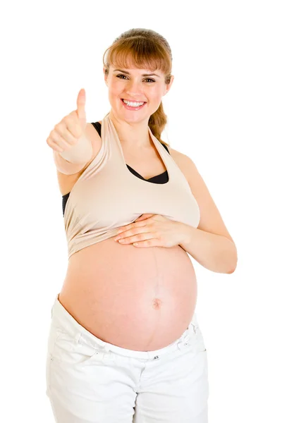 Szczęśliwa kobieta w ciąży dotykając jej brzuch i pokazuje kciuk w górę gest — Zdjęcie stockowe