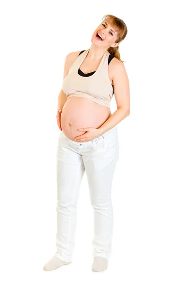 Śmiejąc się kobieta w ciąży trzymając jej brzuch na białym tle — Zdjęcie stockowe