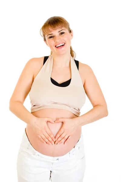 Mujer embarazada sonriente haciendo corazón con las manos en el vientre —  Fotos de Stock
