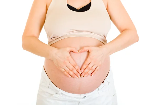 Gravid kvinna att göra hjärta med händerna på magen. närbild. — Stockfoto