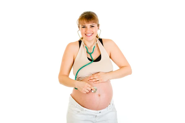 Mujer embarazada sonriente sosteniendo estetoscopio en su barriga —  Fotos de Stock