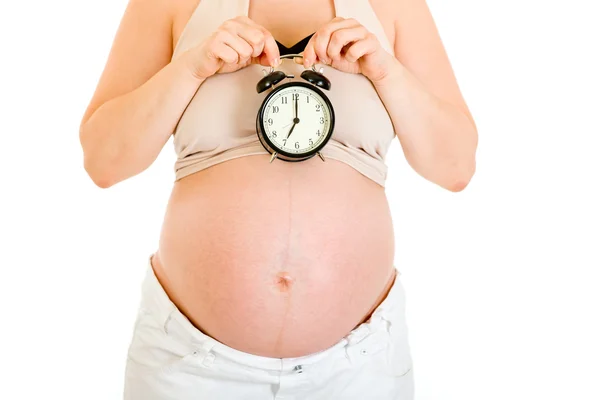 Zwangere vrouw met alarm klok in de buurt van haar buik. Close-up. — Stockfoto