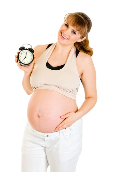 Малыш на подходе! Улыбающаяся беременная женщина держит будильник — стоковое фото