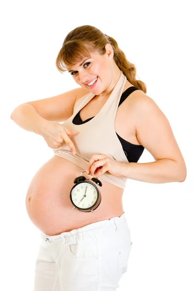 Kobieta w ciąży uśmiechający się wskazujący na budzik — Zdjęcie stockowe