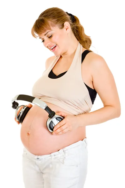 Счастливая беременная женщина с наушниками на животе — стоковое фото