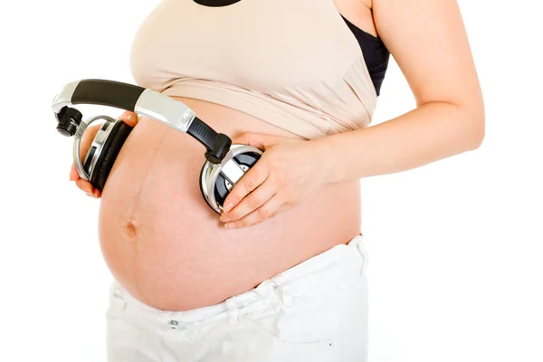 Zwangere vrouw met hoofdtelefoon op haar buik. Close-up. — Stockfoto