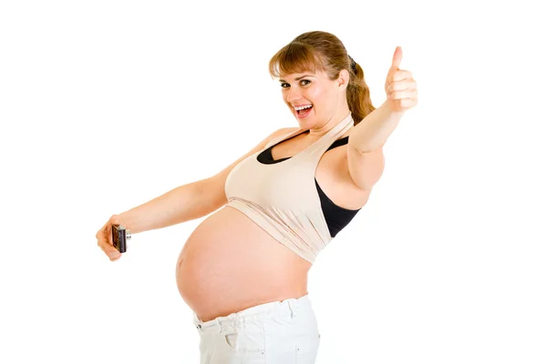 Pregnant woman photographing her belly and showing thumbs up gesture — Stockfoto