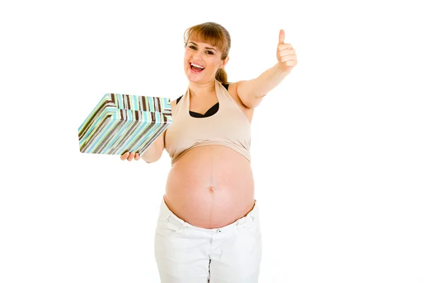 Feliz embarazada sosteniendo regalo para su bebé y mostrando los pulgares hacia arriba gestur — Foto de Stock