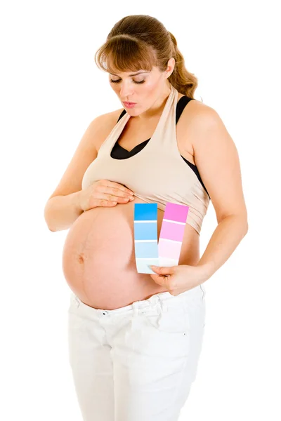Embarazada mujer sosteniendo color pintura samples y soplando beso su vientre —  Fotos de Stock