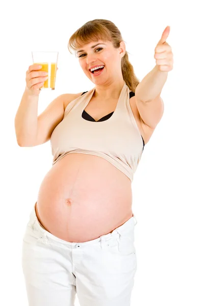 Uśmiechający się kobieta w ciąży trzymając szklankę soku i pokazano kciuki gestur — Zdjęcie stockowe