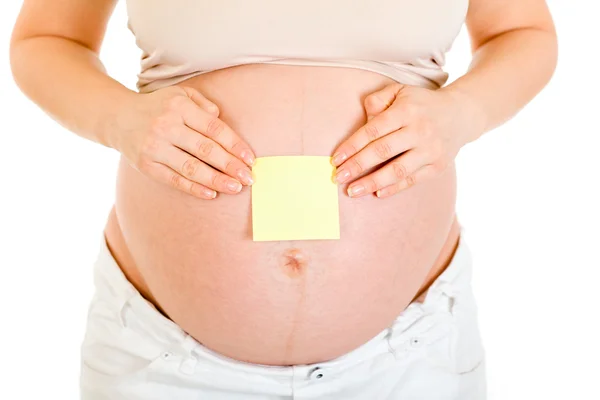 Mujer embarazada con una nota adhesiva en blanco en la barriga. Primer plano . — Foto de Stock