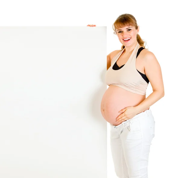 Sonriendo hermosa mujer embarazada sosteniendo la cartelera en blanco — Foto de Stock