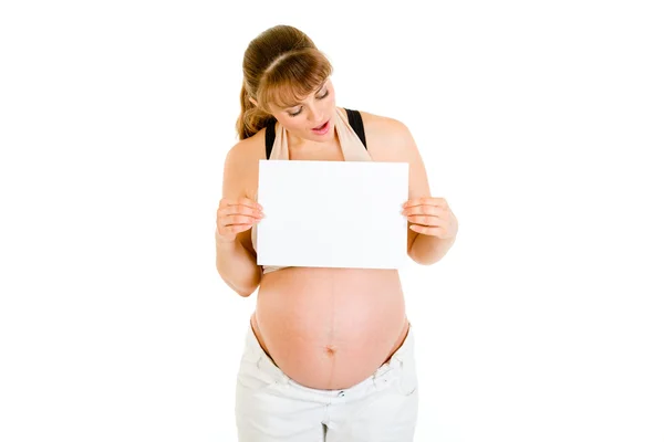Удивлённая беременная женщина смотрит на пустую белую бумагу — стоковое фото
