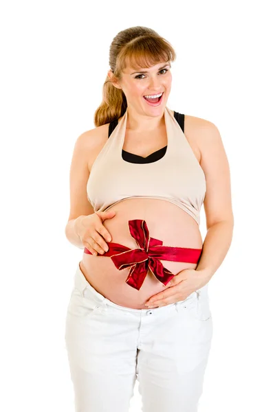 Szczęśliwy piękna kobieta w ciąży z czerwoną wstążką na brzuch — Zdjęcie stockowe