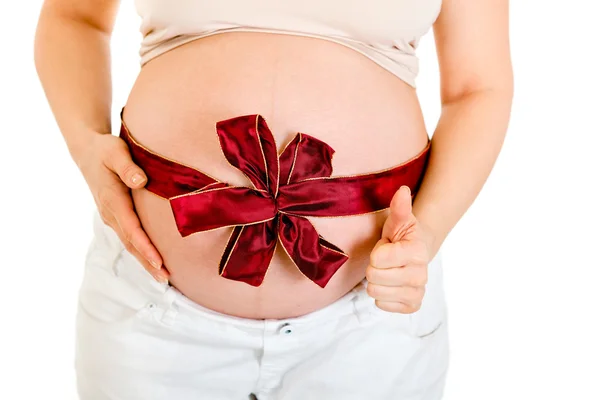 Pregnant woman with red ribbon on belly showing thumb up gesture. Close-up — Stock Photo, Image