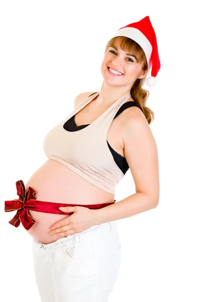 Happy beautiful pregnant woman in Santa hat with red ribbon on belly — Stock Photo, Image