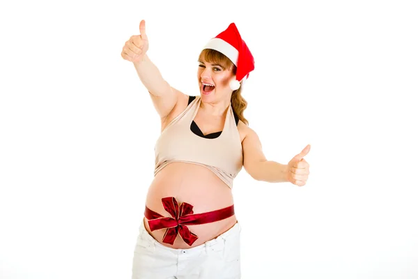 Happy christmas pregnant woman in Santa hat showing thumb up gesture — Stock Photo, Image