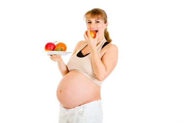 Lachende zwangere vrouw met vruchten in de hand en eten apple — Stockfoto