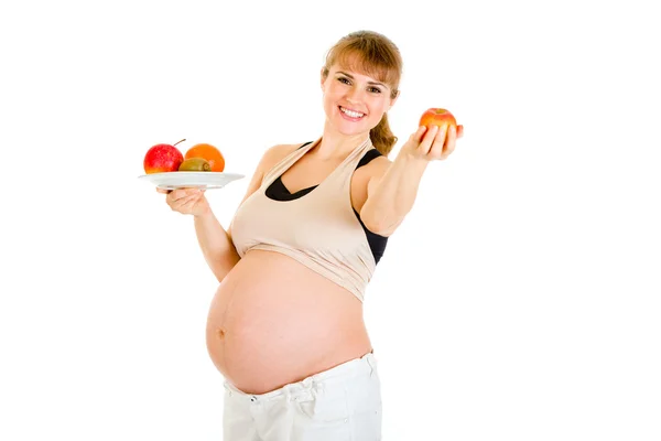 Meyve elinde tutan güzel bir hamile kadın gülümsüyor — Stok fotoğraf