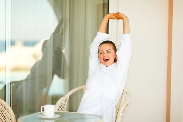 Mooie vrouw in badjas zittend aan tafel op terras en stre — Stockfoto
