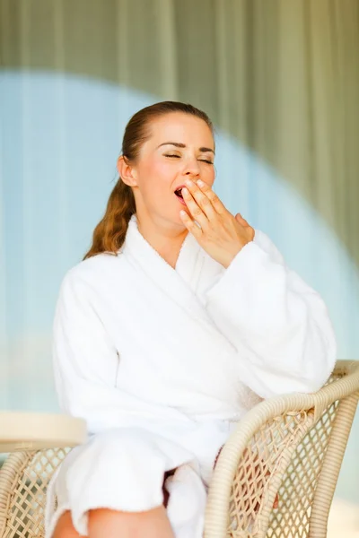 Woman in bathrobe sitting at terrace and yawing — Stock Photo, Image