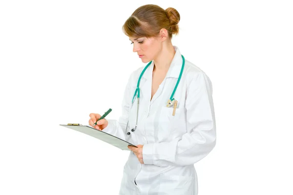 Skoncentrowany kobiece kobieta lekarz robiąc notatki w dokumencie — Zdjęcie stockowe