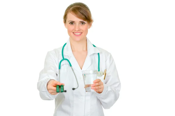 Smiling female medical doctor giving packs of pills and glass of water — Stock Photo, Image