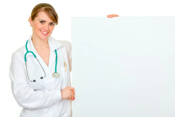 Médico sonriente mujer médico sosteniendo cartelera en blanco —  Fotos de Stock