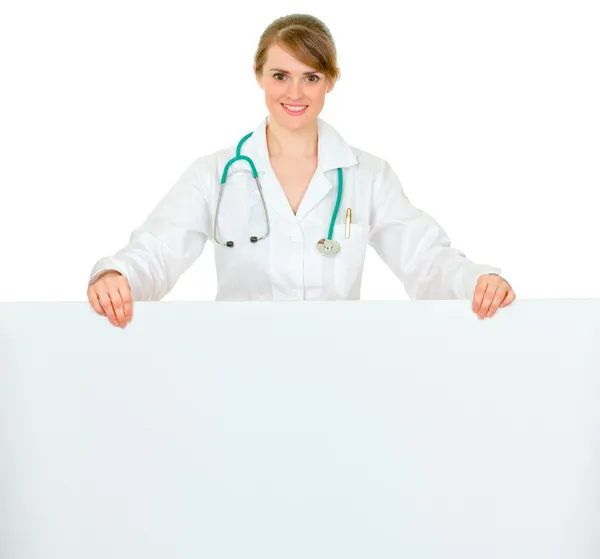 Smiling medical doctor woman holding blank billboard — Stock Photo, Image