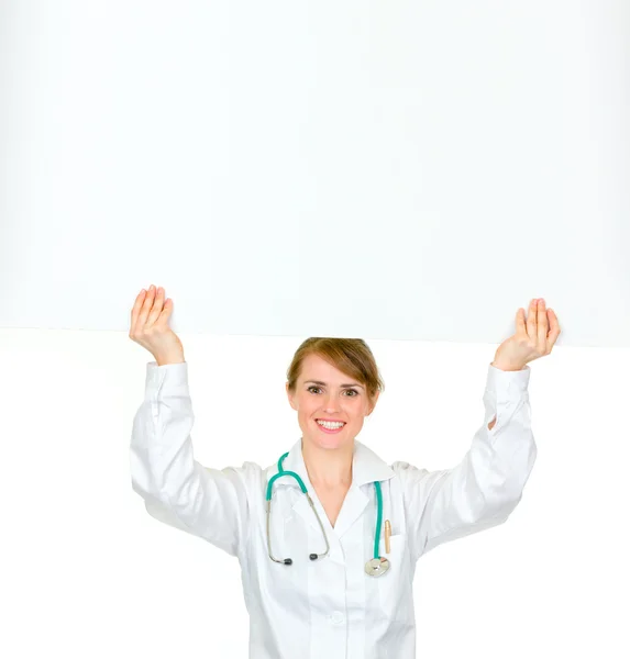 彼女の頭の上のブランクの看板を持った医師女性の笑みを浮かべてください。 — ストック写真
