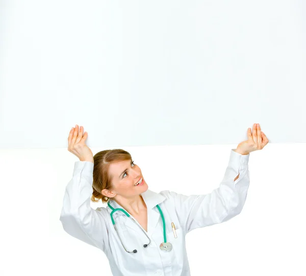 Smiling medical doctor woman looking at blank billboard — Stock Photo, Image