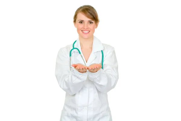 Uśmiechnięta kobieta lekarz, prezentując coś na puste ręce — Zdjęcie stockowe