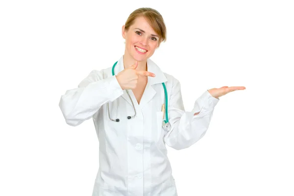 Smiling female medical doctor pointing finger on empty hand — Stock Photo, Image