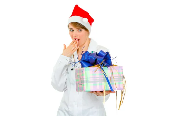 Sorprendido médico mujer en Santa sombrero mirando en el presente b — Foto de Stock