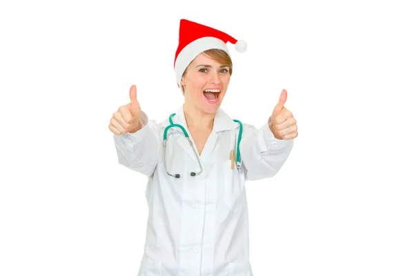 Happy medical doctor woman in Santa hat showing thumbs up gesture — Stock Photo, Image