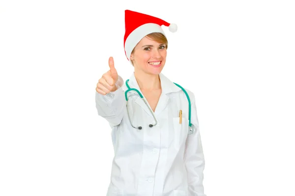 Smiling medical female doctor in Santa hat showing thumbs up — Stock Photo, Image