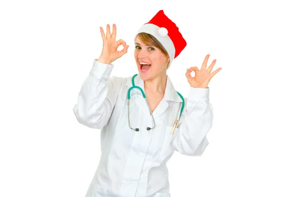 Alegre médico mujer en Santa sombrero mostrando gesto ok — Foto de Stock