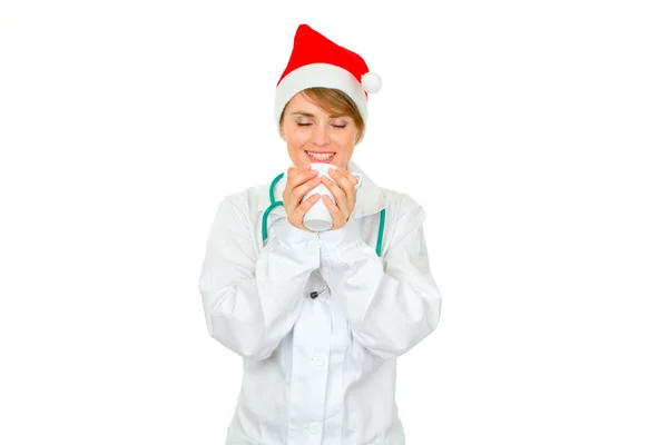 Ευτυχισμένη γυναίκα γιατρός στην το καπέλο santa απολαμβάνοντας το ζεστό φλιτζάνι καφέ — Φωτογραφία Αρχείου