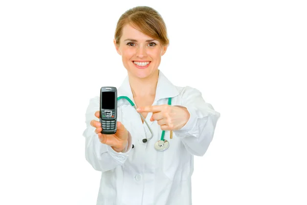 Smiling medical female doctor pointing finger on mobile with blank screen — Stock Photo, Image