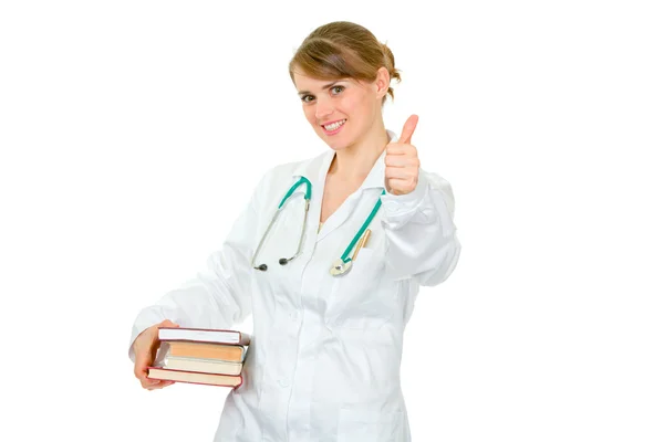 Sorridente giovane medico femminile che tiene diversi libri in mano — Foto Stock