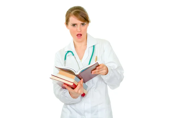 Confused medical female doctor with pile of books — Stock Photo, Image