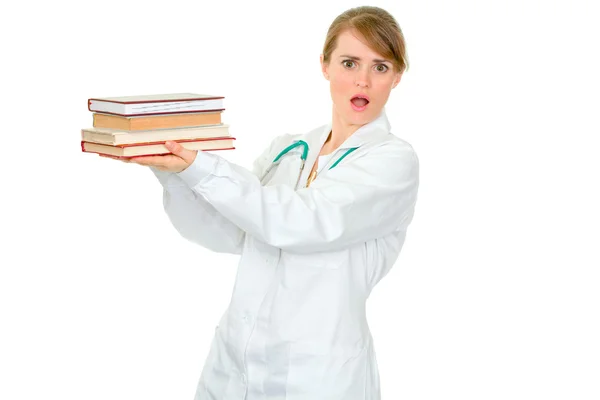 Σοκαρισμένος νεαρή γυναίκα γιατρό κρατώντας διάφορα ιατρικά βιβλία στα χέρια — Φωτογραφία Αρχείου